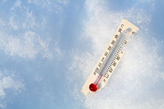Glass bulb thermometer lying on snow background with copy space