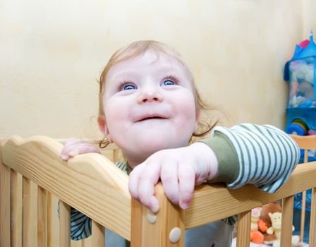 Happy baby boy looking up out of his bed