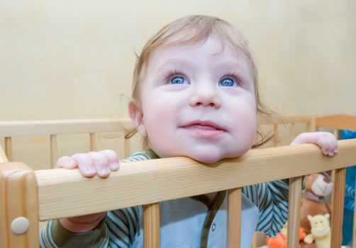 Funny baby boy looking curiously out of bed