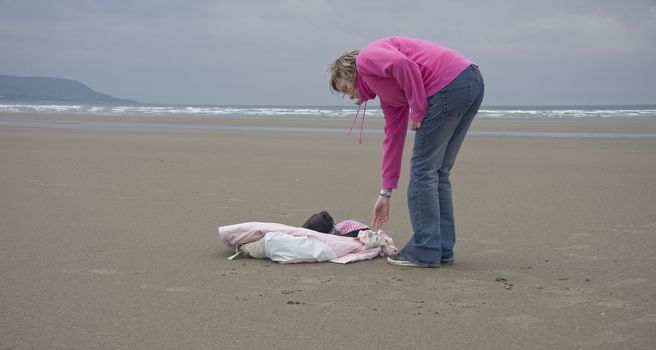 Young girl picking up her things on the beach in wales.