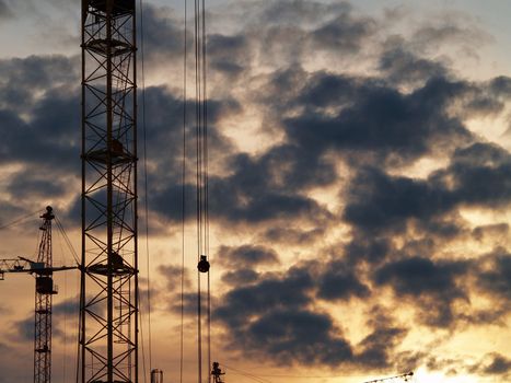 Elevating cranes and sky. Sunset after rain.     