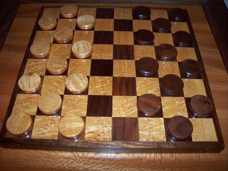 A wooden checker board on a wood table