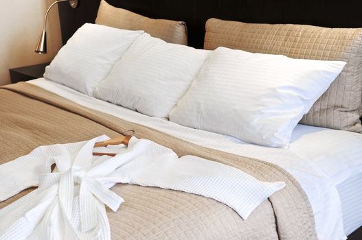 Comfortable bed with clean bathrobe in upscale hotel