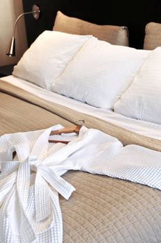 Comfortable bed with clean bathrobe in upscale hotel