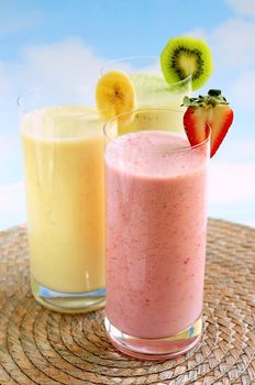 Assorted fruit and berry smoothies on blue sky background