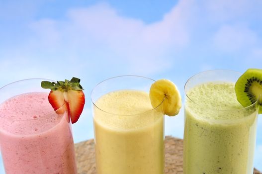 Assorted fruit and berry smoothies on blue sky background