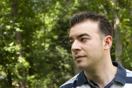 A young Italian man with spiked hair standing in front of a wooded background.