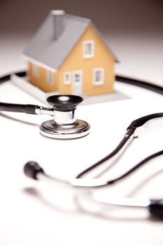 Stethoscope and Model House on Gradated Background with Selective Focus.