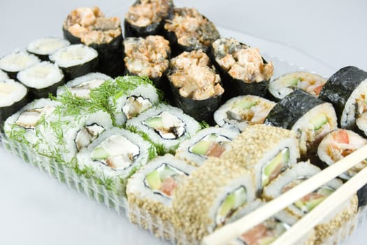 traditional japanese rolls and sushi with sticks on gray