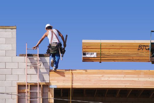 Carpenter climbing up ladder at a construction scene.
