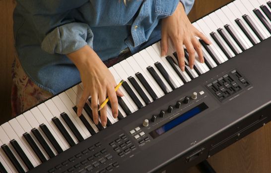 Woman's Fingers with Pencil on Digital Piano Keys