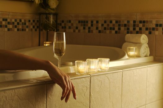 Beautiful Woman in bubble bath with sparkling wine and candles surrounding her. 