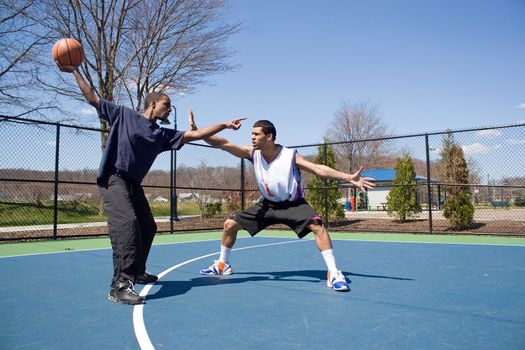 A young basketball player guarding his opponent during a one on one basketball game.