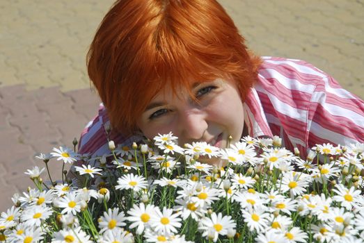 Beautiful woman hugs many flowers chamomile outdoor