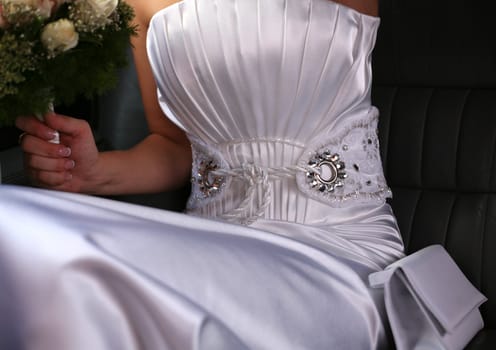 The bride with a wedding bouquet and a bag in the car