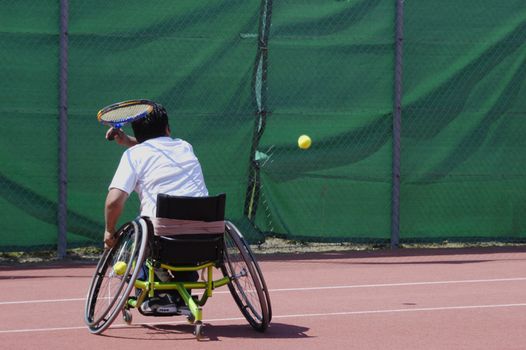 A wheelchair tennis player during a tennis championship match, taking a shot.