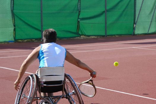 A wheelchair tennis player during a tennis championship match, taking a shot.