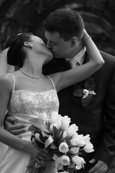 Beautiful the bride and the groom kiss in park