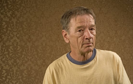 Man with a craggy face wearing a yellow shirt against a gold background with copy space