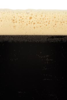 A macro image of a glass of stout beer or bitter.
