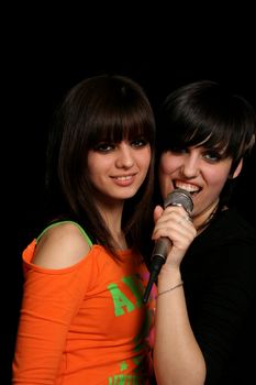 Two girls with a microphone, on black background
