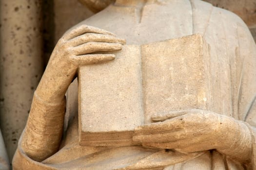 Medieval statue's detail with hands and book