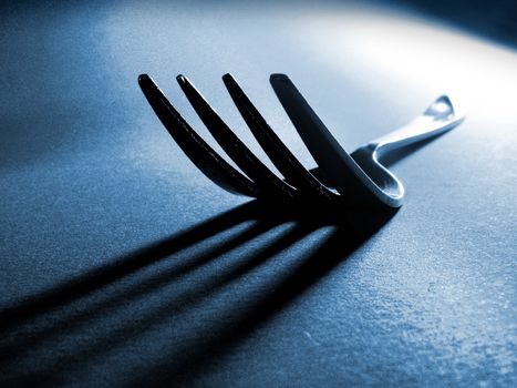 Fork and long shadow against textured background
