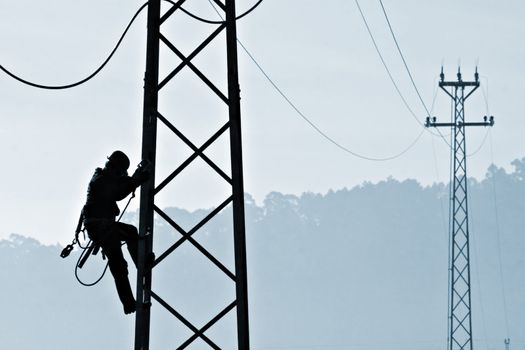 Backlit powerplant worker descending from tower