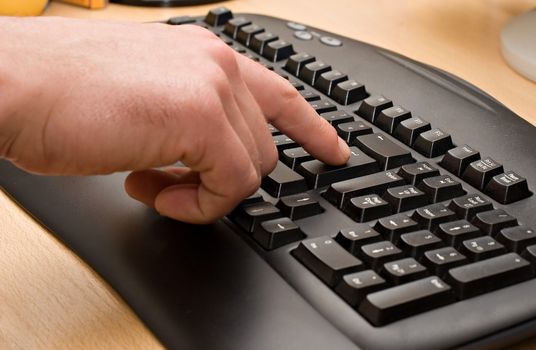 Typing. Pressing Enter Key. Black keyboard on wooden table.