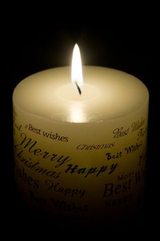 Lit white Christmas candle on black background