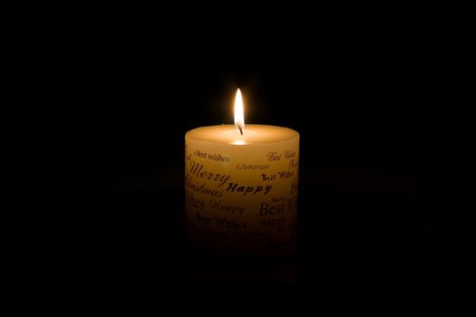 White Christmas candle lit on black background