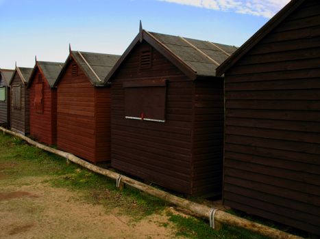 Close view of row of beach huts on sand dunes. Deserted during the winter months.