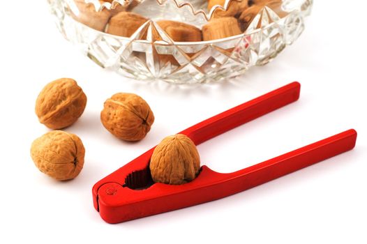 Red nutcraker with walnuts and glass bowl isolated on white with shallow depth of field