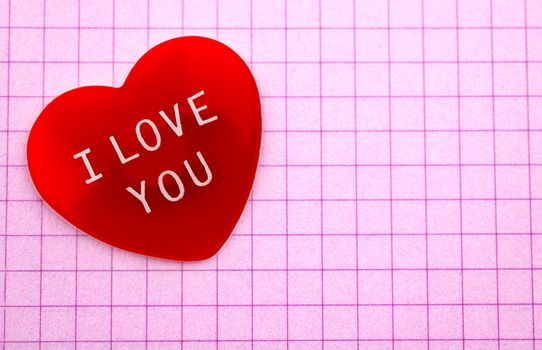 Red heart with I Love You message on pink chequered sheet of paper with copy space 