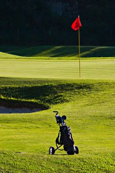 Golf bag near golf green, with pole and red flag