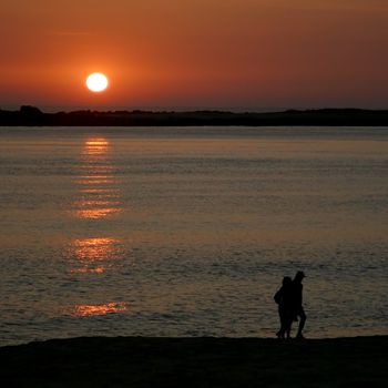 Couple walking on beach at sunset