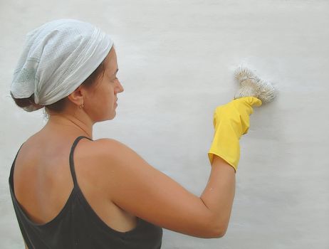 The woman in yellow mittens with a brush in hands on a white background