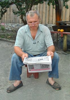 Elderly rural the man closely reads the newspaper. He is interested what else a  politicians have presented surprise
