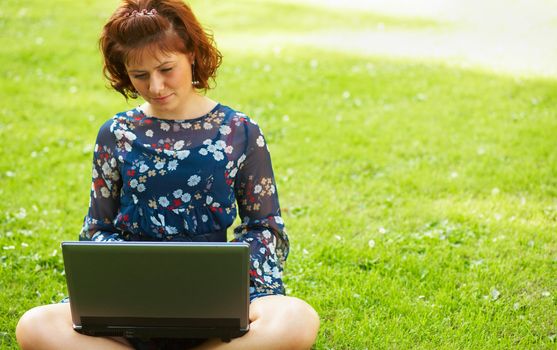 Young woman working on her laptop in nature.