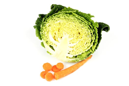 Half a raw green cabbage with a single chopped carrot on a reflective white background