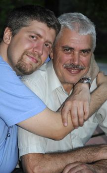 Adult son hugs his senior father outdoor