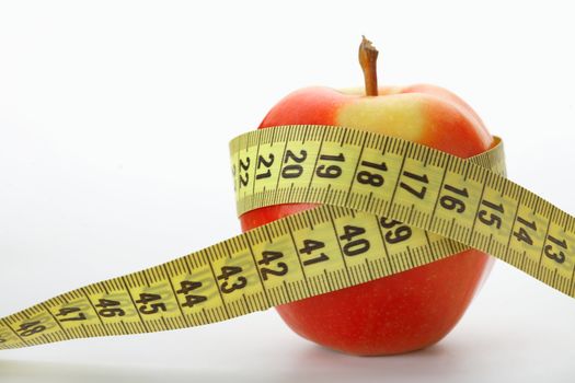 Red apple with a measuring tape on white