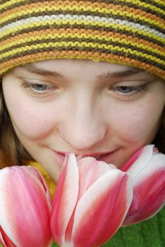 Girl in striped cap and face in pink tulips.