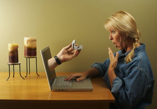 Attractive woman surprised with her online proposal and ring coming through her laptop screen.