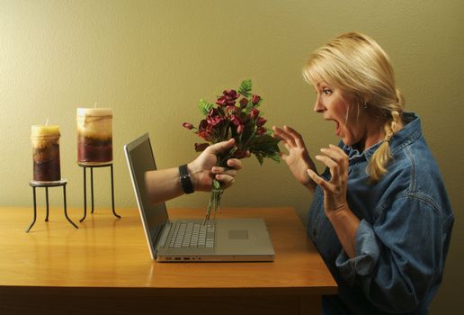 Attractive woman stunned from the flower handed to her coming through her laptop screen.
