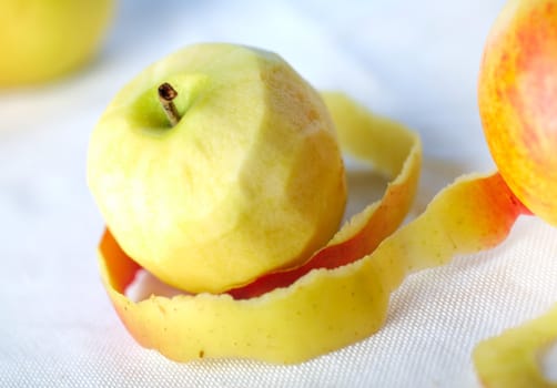 Yellow apple with peeled twisted skin against other apples