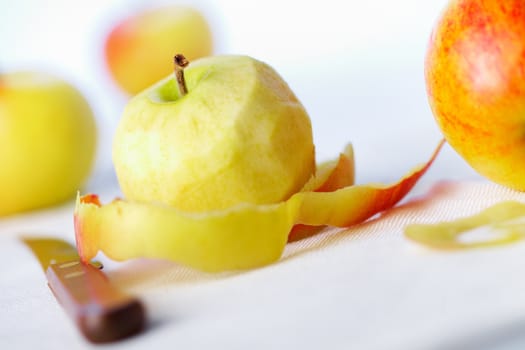 Yellow apple with peeled twisted skin against other apples