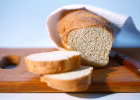 Bread with three slices on light blue background.