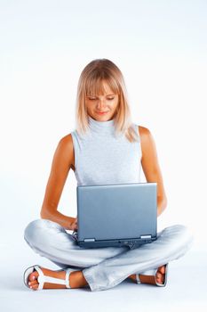 Smiling woman sitting with her legs crossed on the floor with laptop