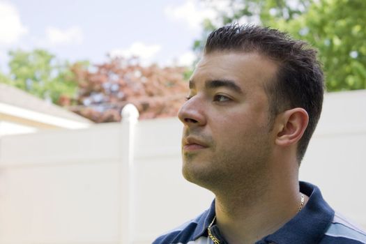 A young Italian man with spiked hair outside in the backyard.